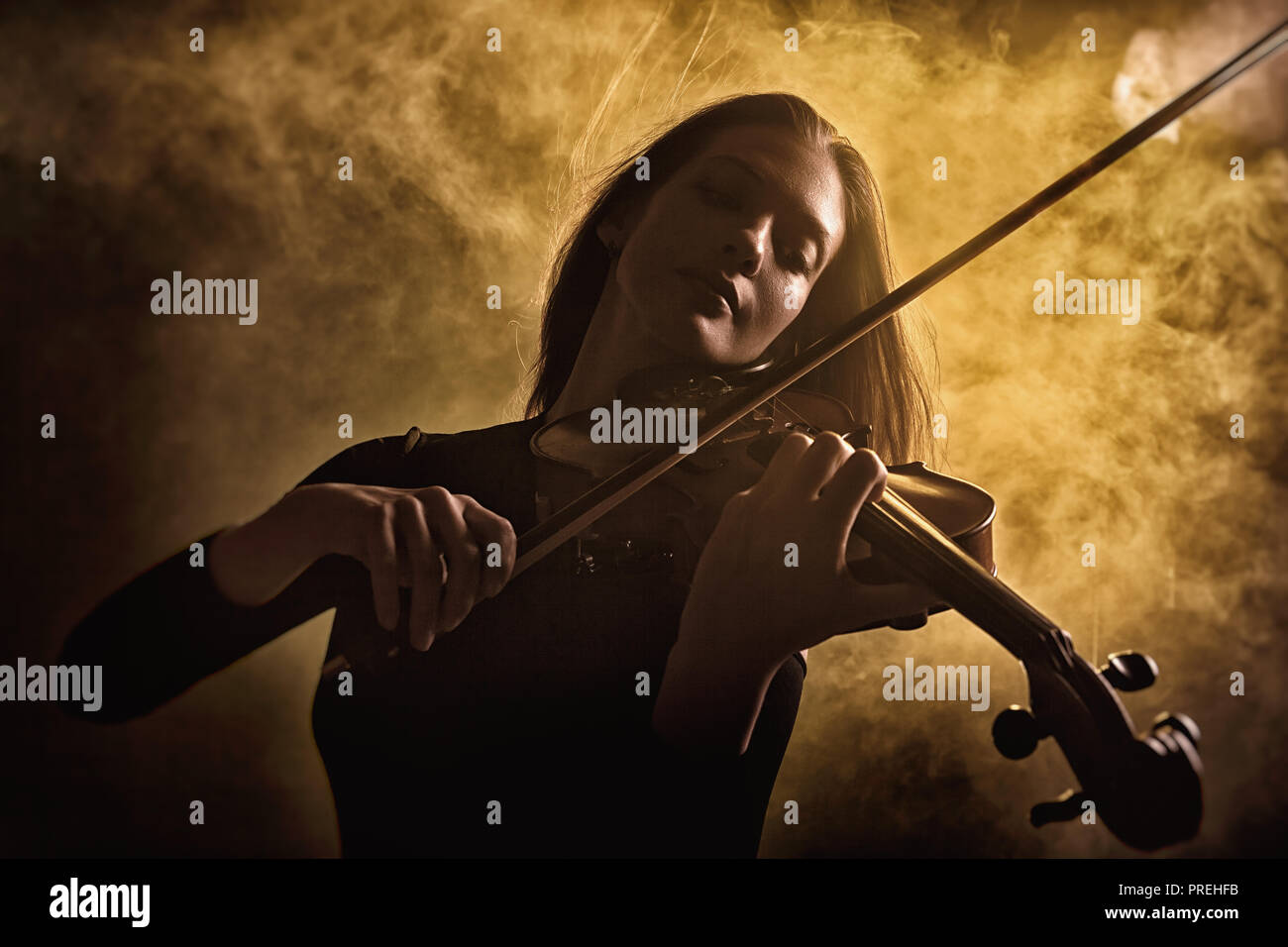 Ragazza a suonare il violino contro uno sfondo scuro. La nebbia in background. Studio shot Foto Stock