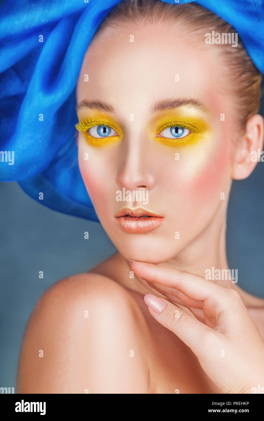 Ritratto di una donna bellissima con la moda per il make-up, luminoso giallo in polvere negli occhi e dŽcor blu sul suo capo Foto Stock