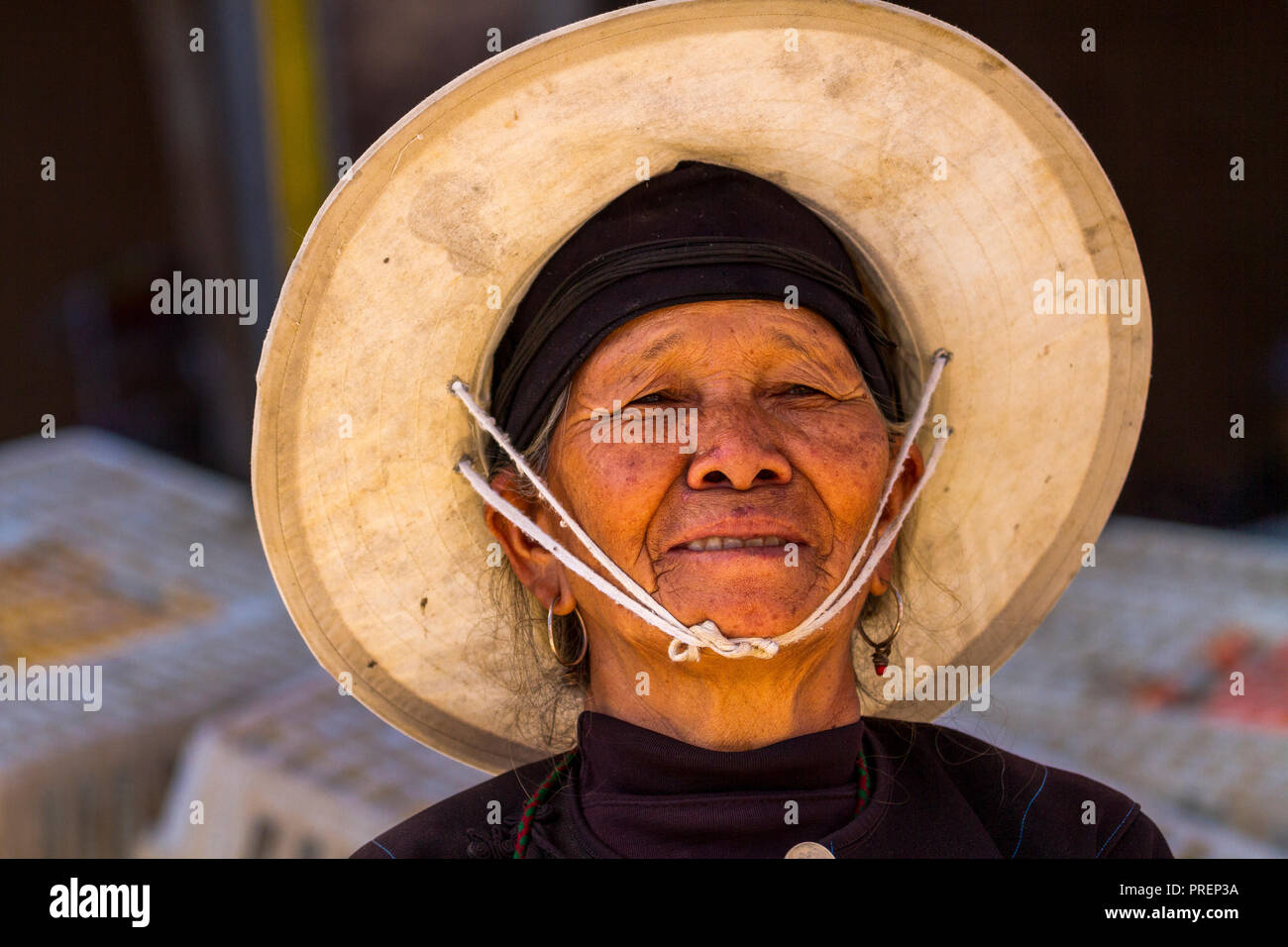 L'agricoltore cinese donna che indossa cappello di paglia al mercato nelle zone rurali Niujiaozhai town, Yuanyang nella provincia di Yunnan, Cina del sud. Foto Stock