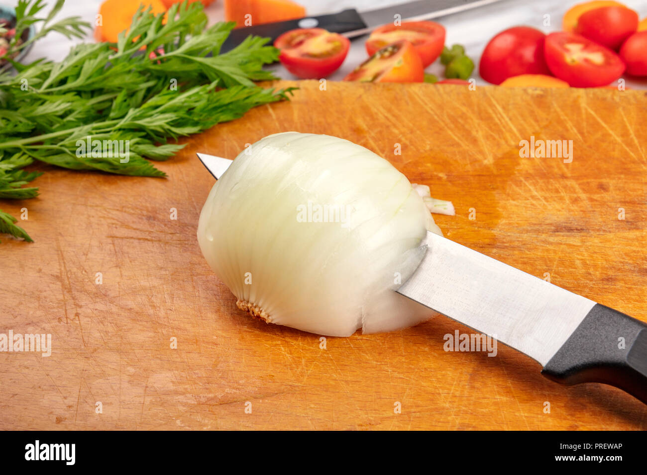Abilità di coltello, uno chef professionale coltello per il taglio di una cipolla su una tavola di legno durante il tempo di preparazione, mise en place Foto Stock