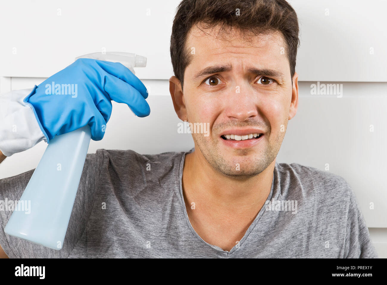 Giovane marito in crisi i lavori di casa. Close up ha sottolineato l uomo con apparecchiature per la pulizia Foto Stock