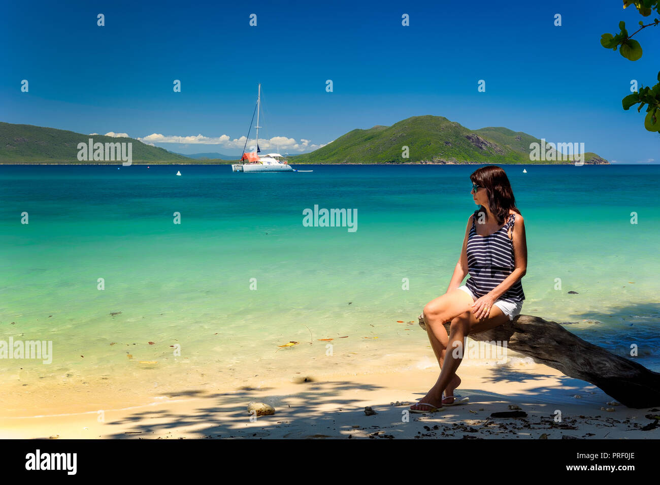 Un turista si appoggia su una spiaggia nelle acque cristalline di Fitzroy isola tropicale Nord Queensland. Foto Stock