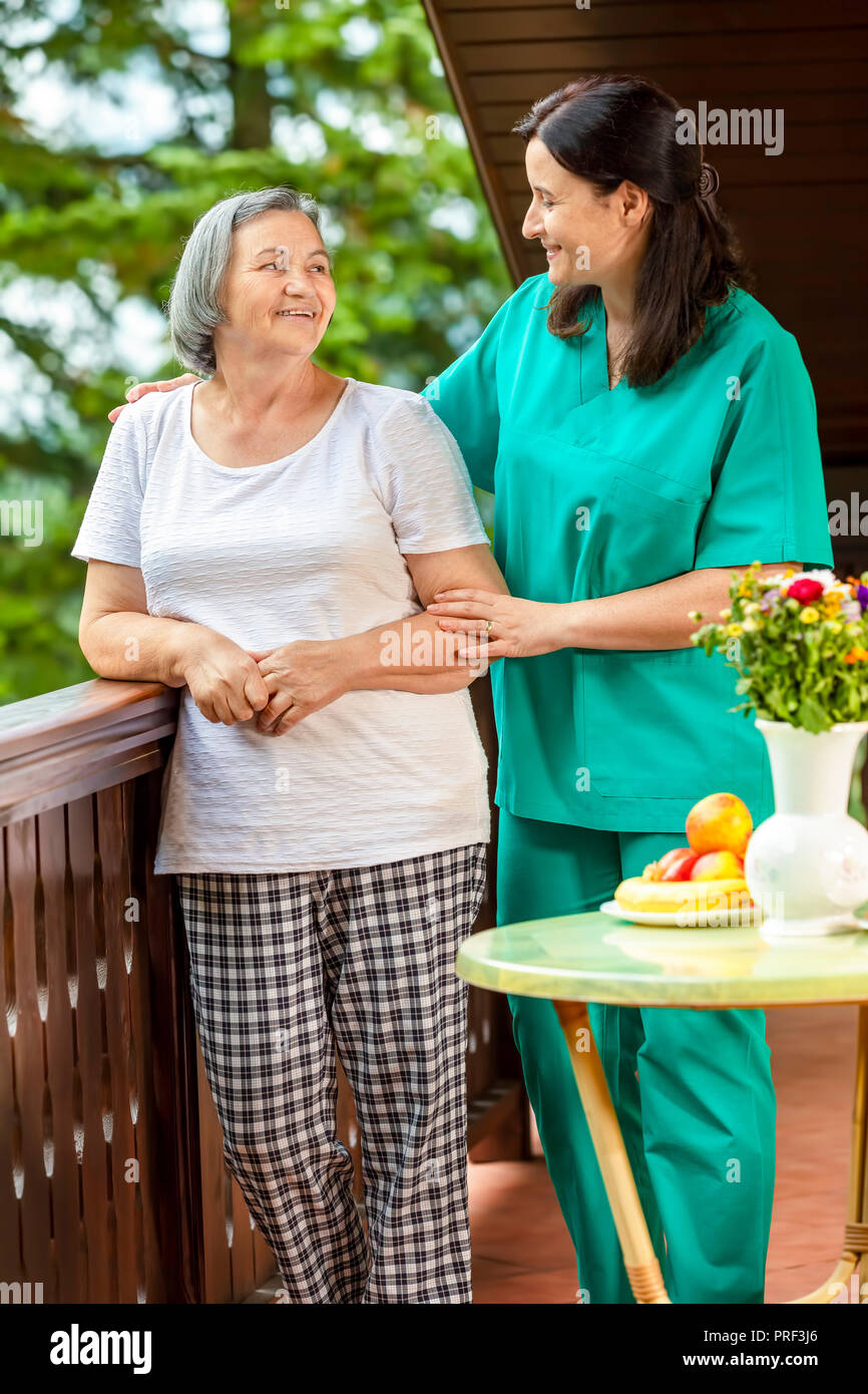 Donna senior con la sua casa caregiver di trascorrere del tempo insieme. Femmina consolante infermiere donna senior a casa. Foto Stock