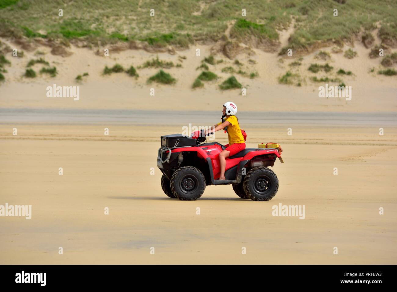 ATV quad bike essendo cavalcato da un bagnino RNLI,Perranporth beach,Cornwall,l'Inghilterra,UK Foto Stock