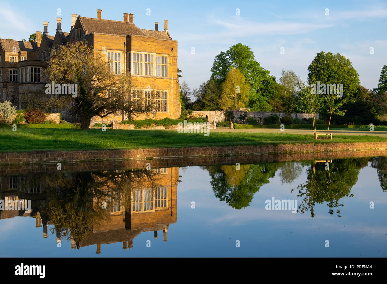 Castello di Broughton, vicino a Banbury, casa della famiglia Fiennes in golden luce della sera con riflessi nell'acqua ancora del fossato. Aperta al pubblico Foto Stock