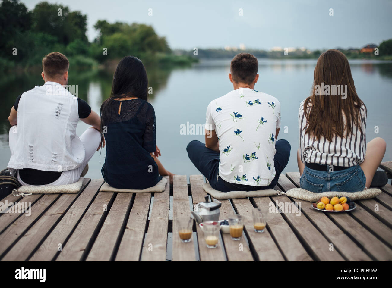 Vista posteriore di amici rilassante sul fiume Pier. La vacanza estiva concept Foto Stock