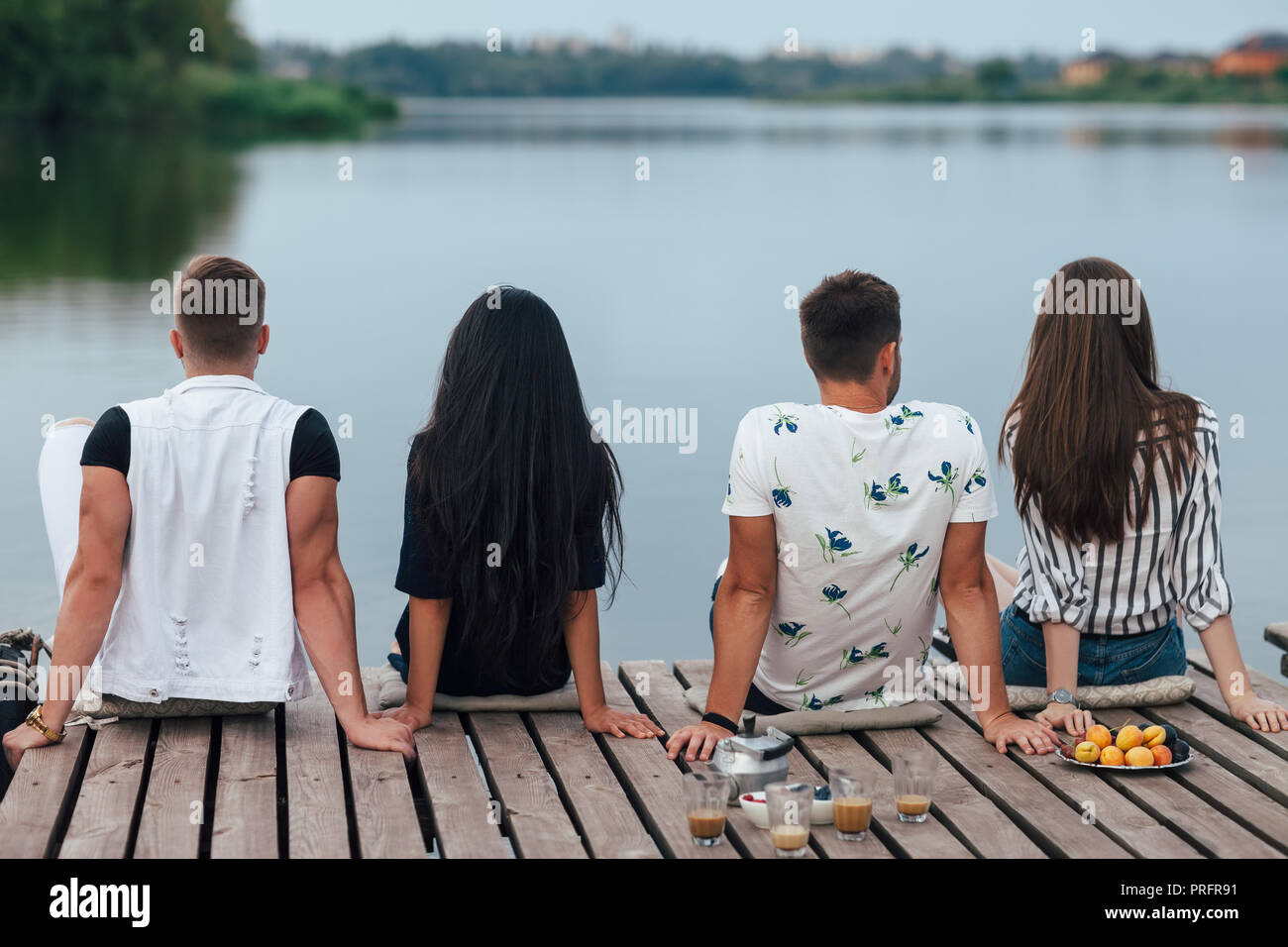 Vista posteriore di amici rilassante sul fiume Pier. La vacanza estiva concept Foto Stock