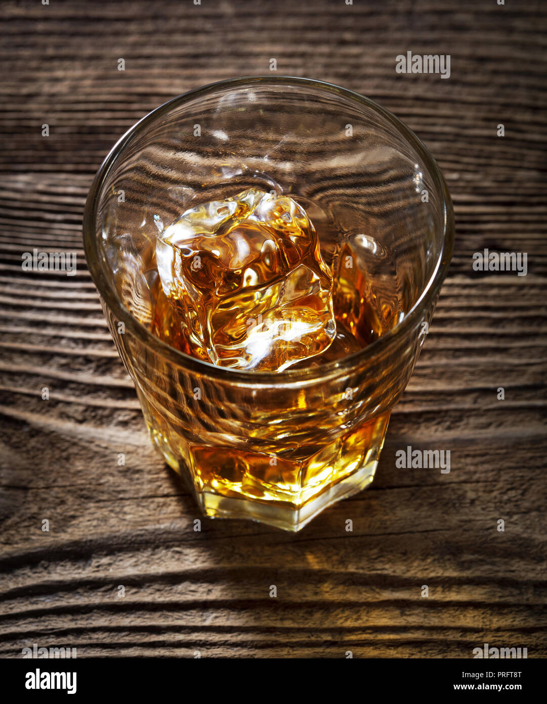 Singolo bicchiere di alcol bevande con ghiaccio su sfondo di legno Foto Stock