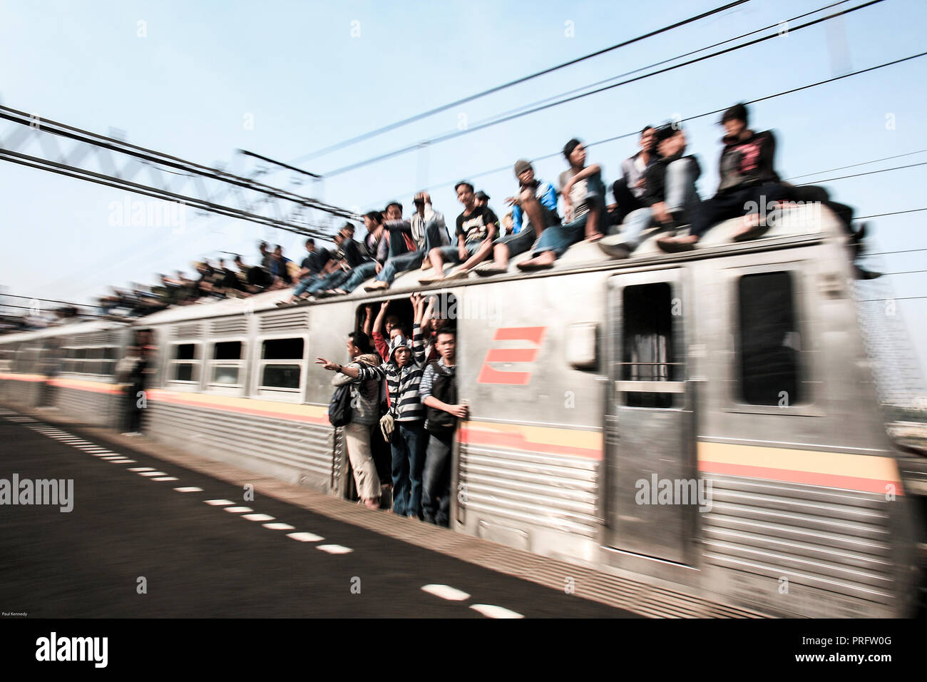 Giovani uomini che cavalcano in cima alla folla Mass Rapid Transit treno a Giacarta, Java, Indonesia Foto Stock
