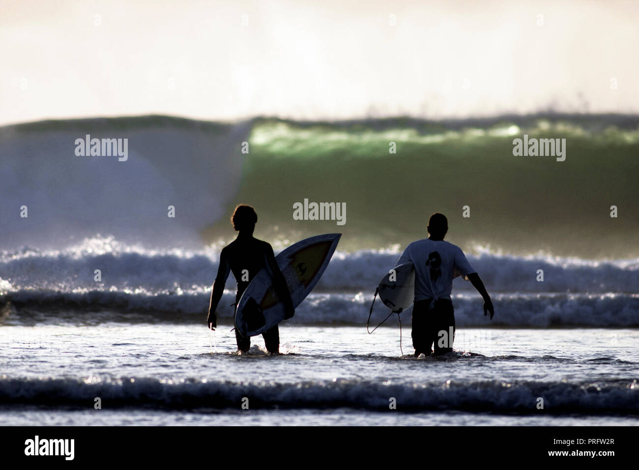 Surfers trampolieri fuori per navigare in grandi onde a Grajagan Bay, Java, Indonesia Foto Stock