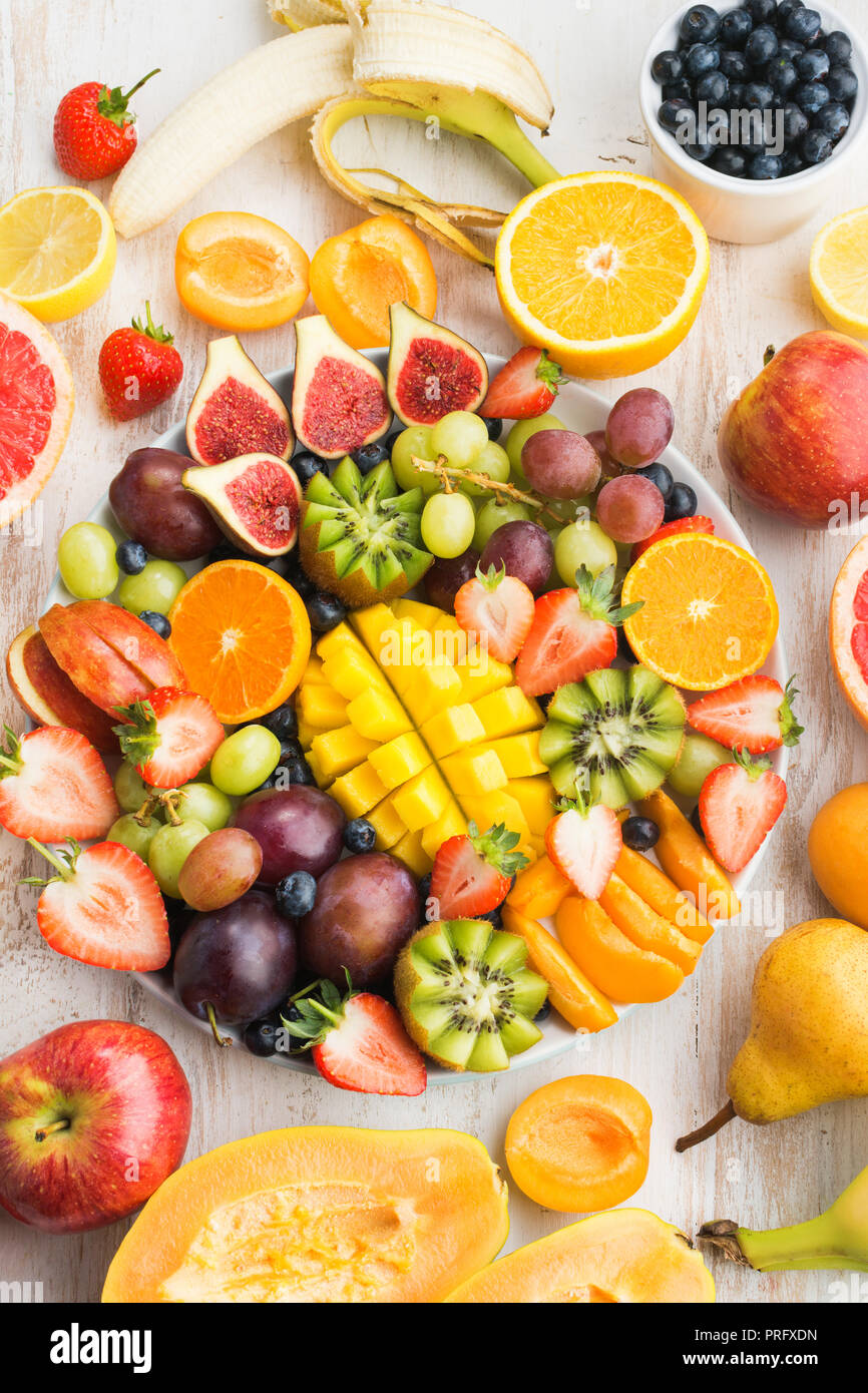 Frutti e bacche platter, fragole mirtilli, mango orange, Apple, uva da tavola, kiwi sul bianco Sfondo legno, copia spazio, vista dall'alto Foto Stock