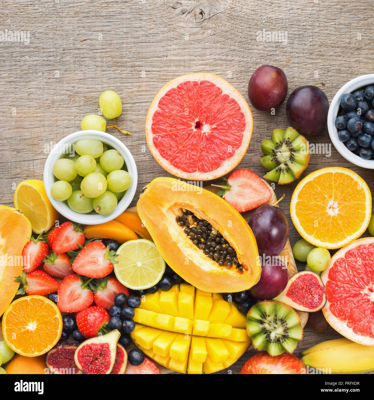 Frutti colorati, fragole mirtilli, mango orange, pompelmo, banana papaya apple, uva da tavola, kiwi sullo sfondo legno, copia spazio per il testo Foto Stock