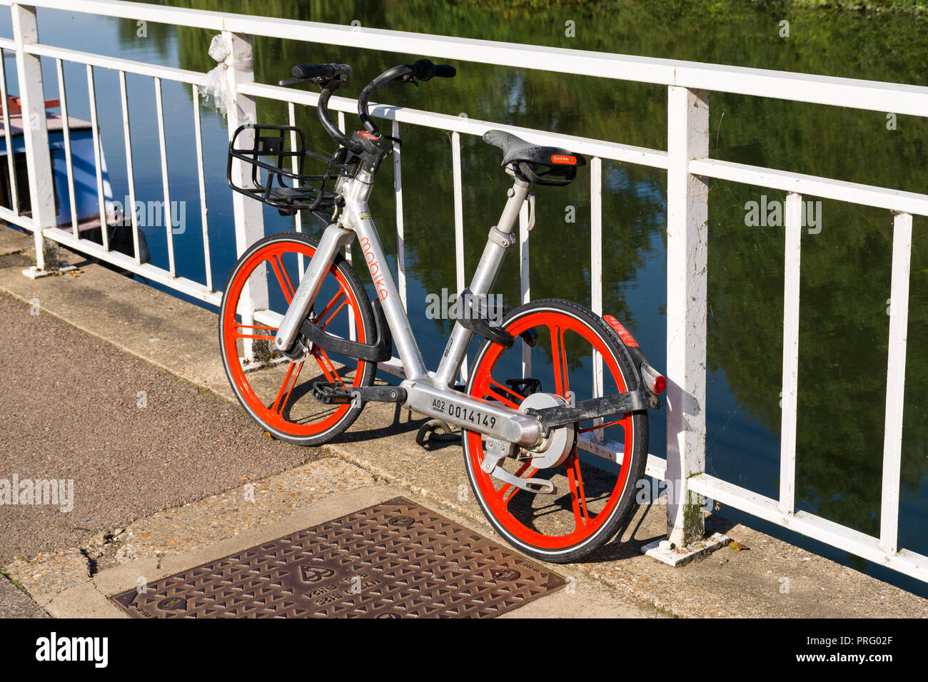 Un Mobike bike schema di condivisione bike appoggiata contro le ringhiere in bianco con il fiume Cam in background, Cambridge, Regno Unito Foto Stock