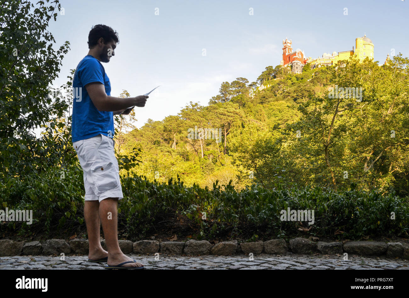 Giovane (20-25) azienda turistica una mappa mentre guardando verso l'alto la pena Palazzo Nazionale, un palazzo Romanticist in Sao Pedro de Penaferrim, Sintra Portogallo Foto Stock
