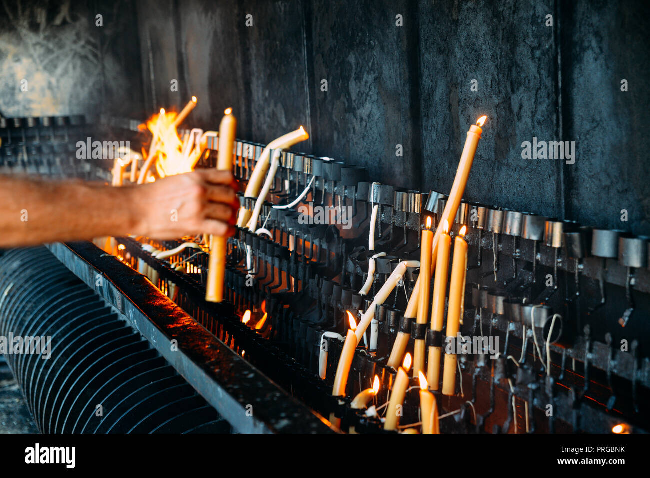 Persona non identificabili accendere una candela su un grande pezzo di cera - la fede religiosa concept Foto Stock