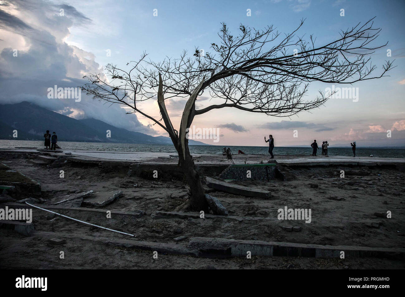 Palu, Sulawesi centrali, Indonesia. 2 Ottobre, 2018. La gente sulla spiaggia accanto a Lone Tree permanente a Palu, dopo la grandezza 7.5 il terremoto e lo tsunami ha colpito la zona del 28 settembre. Il governo indonesiano il 2 ottobre detto il tributo di morte pagato un devastante terremoto tsunami-sull' isola di Sulawesi era salito a 1.550 confermato morto. Servizi di emergenza il timore che il bilancio delle vittime potrebbe salire in migliaia di squadre di soccorso si è messa in contatto con la vicina città di Donggala e Mamuju e forti scosse di assestamento continuano a scuotere la città. Credito: Ivan Damanik/ZUMA filo/Alamy Live News Foto Stock