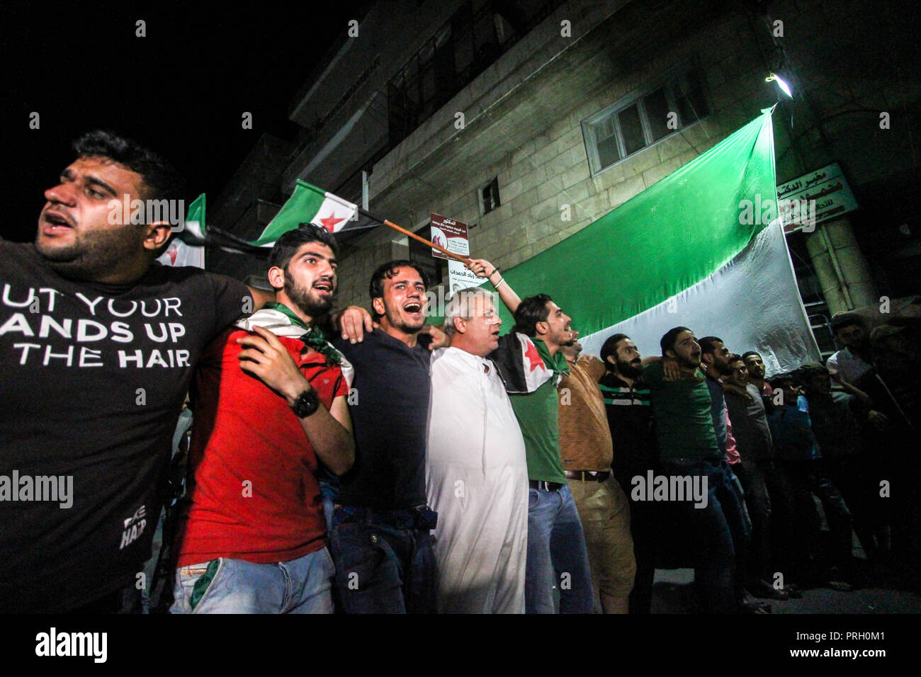 Idleb, Siria, Nord Siria. 2 Ottobre, 2018. Protester visto ringhiera di fronte a una grande free flag siriano durante la dimostrazione.Migliaia di manifestanti sono scesi in strada durante una serata di dimostrazione in Idlib città libertà esigente per il protocollo prigionieri imprigionati dal regime siriano. Essi sono anche le grida anti regime slogan e impegnativo il presidente Assad step-down. Credito: Muhmmad Al-Najjar SOPA/images/ZUMA filo/Alamy Live News Foto Stock