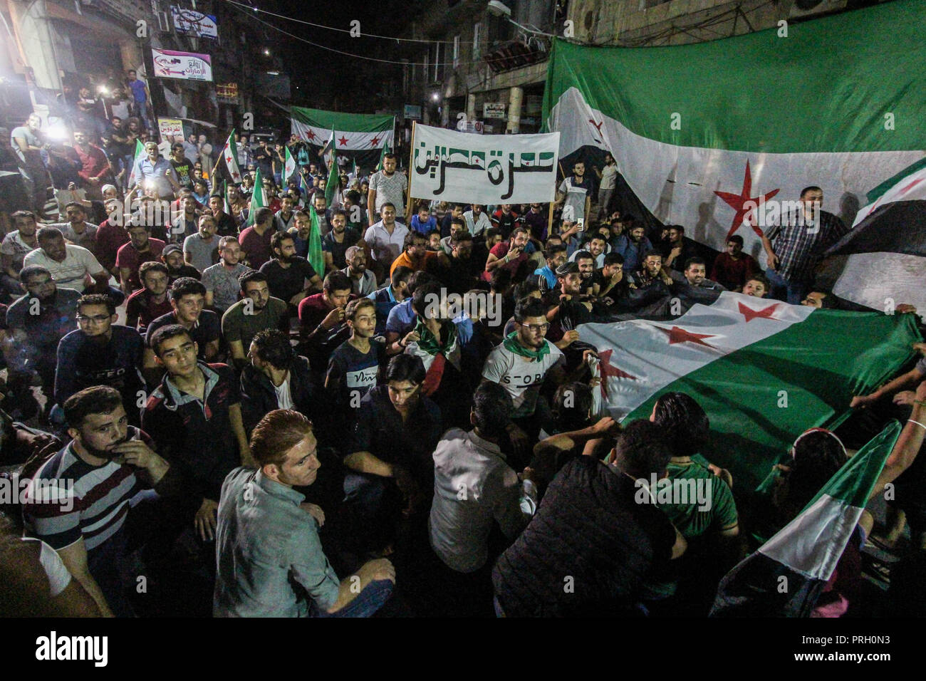 Idleb, Siria, Nord Siria. 2 Ottobre, 2018. Manifestanti hanno visto sventolare il siriano libero di bandiere e cartelli durante la dimostrazione.Migliaia di manifestanti sono scesi in strada durante una serata di dimostrazione in Idlib città libertà esigente per il protocollo prigionieri imprigionati dal regime siriano. Essi sono anche le grida anti regime slogan e impegnativo il presidente Assad step-down. Credito: Muhmmad Al-Najjar SOPA/images/ZUMA filo/Alamy Live News Foto Stock