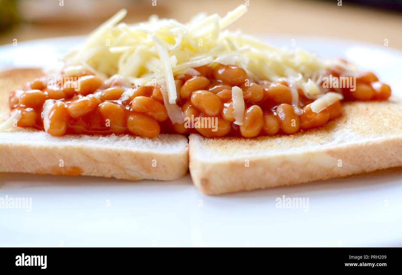 Fagioli su pane bianco tostato condito con formaggio Cheddar grattugiato Foto Stock