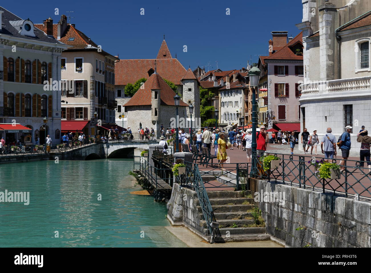 Passi giù per il fiume Thiou e vista in lontananza il Palais de I'lle Annecy Francia Foto Stock