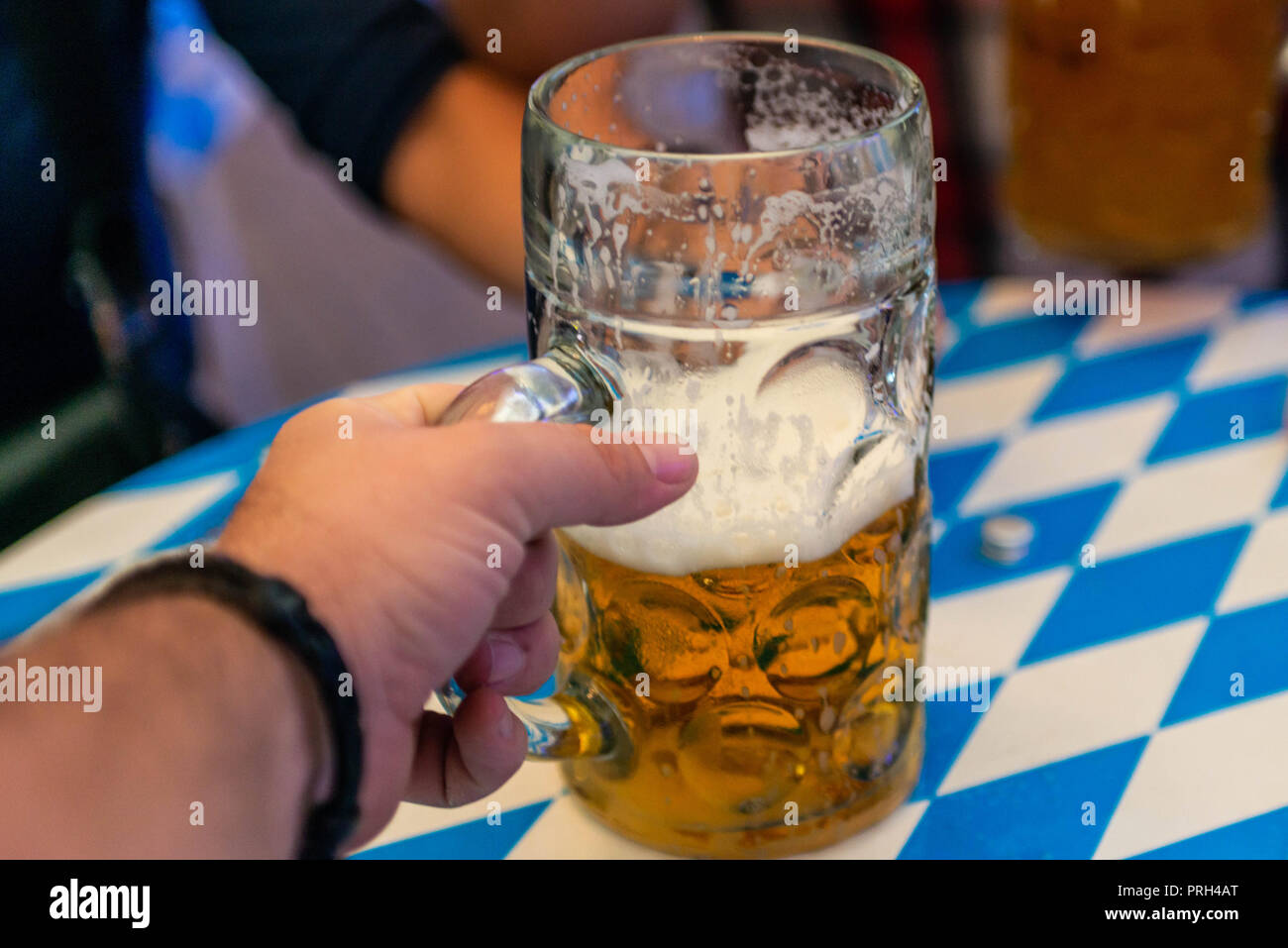Mano di giovani sollevamento di bicchieri di birra al Oktoberfest Germania soft focus. DOF poco profondo. Foto Stock