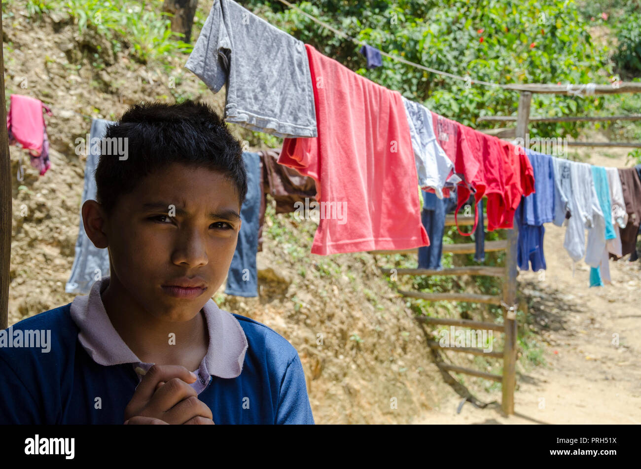 Un ragazzo con i vestiti di essiccazione al sole, sfruttando il calore dei Caraibi, per ottenere vestiti puliti Foto Stock