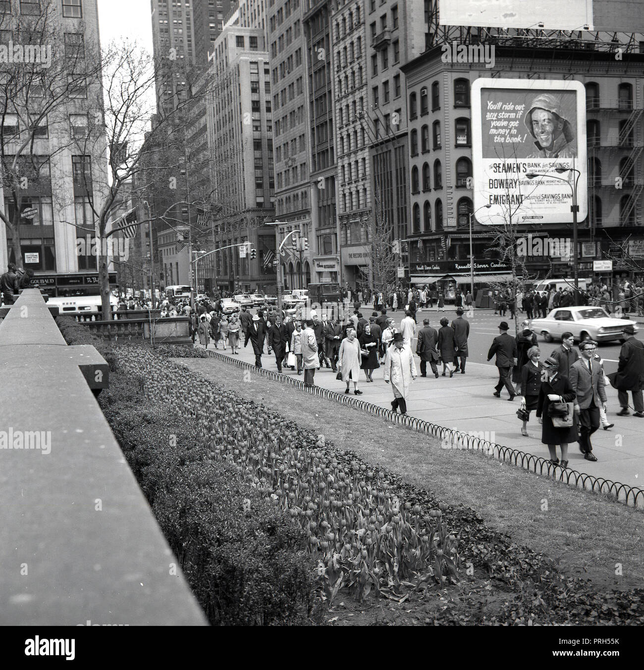 Anni sessanta, storico, immagine mostra i newyorkesi in financia o distretto bancario della città di New York, Wall Street, e un cartellone per noi tre casse di risparmio - il marinaio della banca per il risparmio, il Bowery risparmio bancario e industriale di emigrati risparmio bancario. Foto Stock