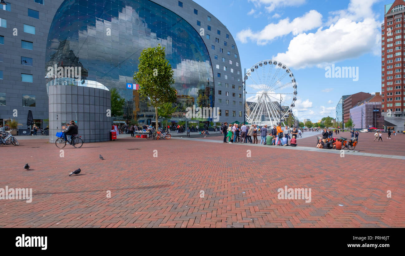 Vista al di fuori del mercato hall di Rotterdam con una grande ruota panoramica Ferris e gruppi di persone e ciclisti sulla piazza di fronte al palazzo Foto Stock
