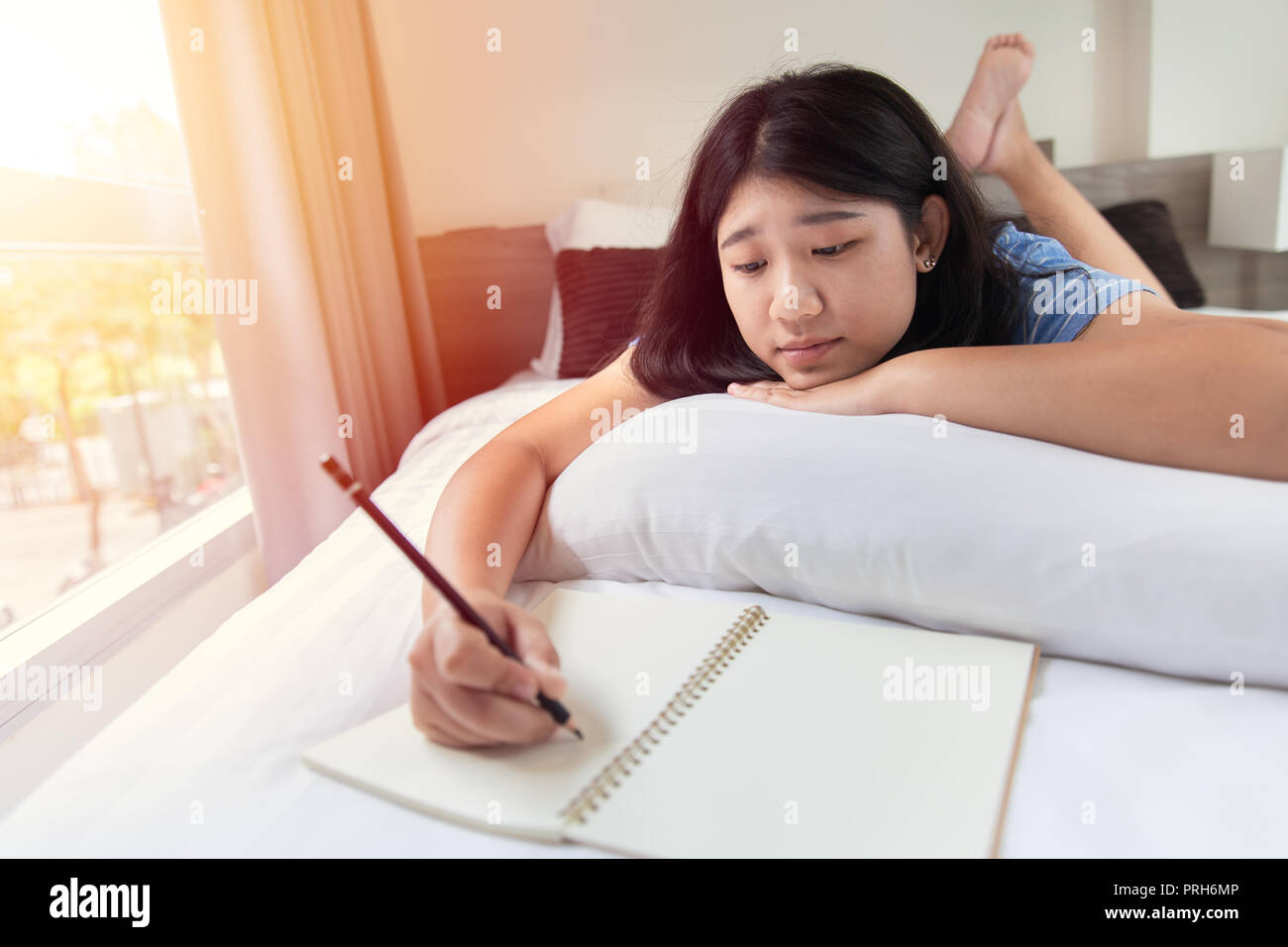 Girl Teen rilassarsi facendo i compiti a casa sul letto in camera da letto al mattino tutti i giorni Foto Stock