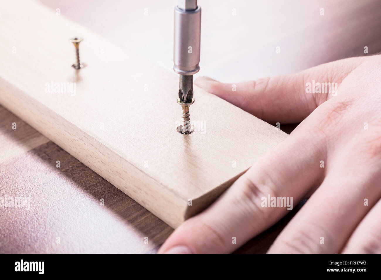 Artigiano azionante una vite in un pezzo di legno Foto Stock