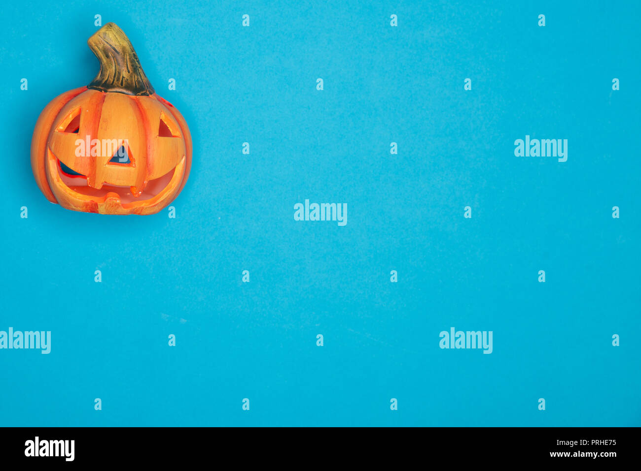 Halloween singola zucca scolpita divertenti e simpatici volti. Simbolo di autunno contro sfondo blu Foto Stock