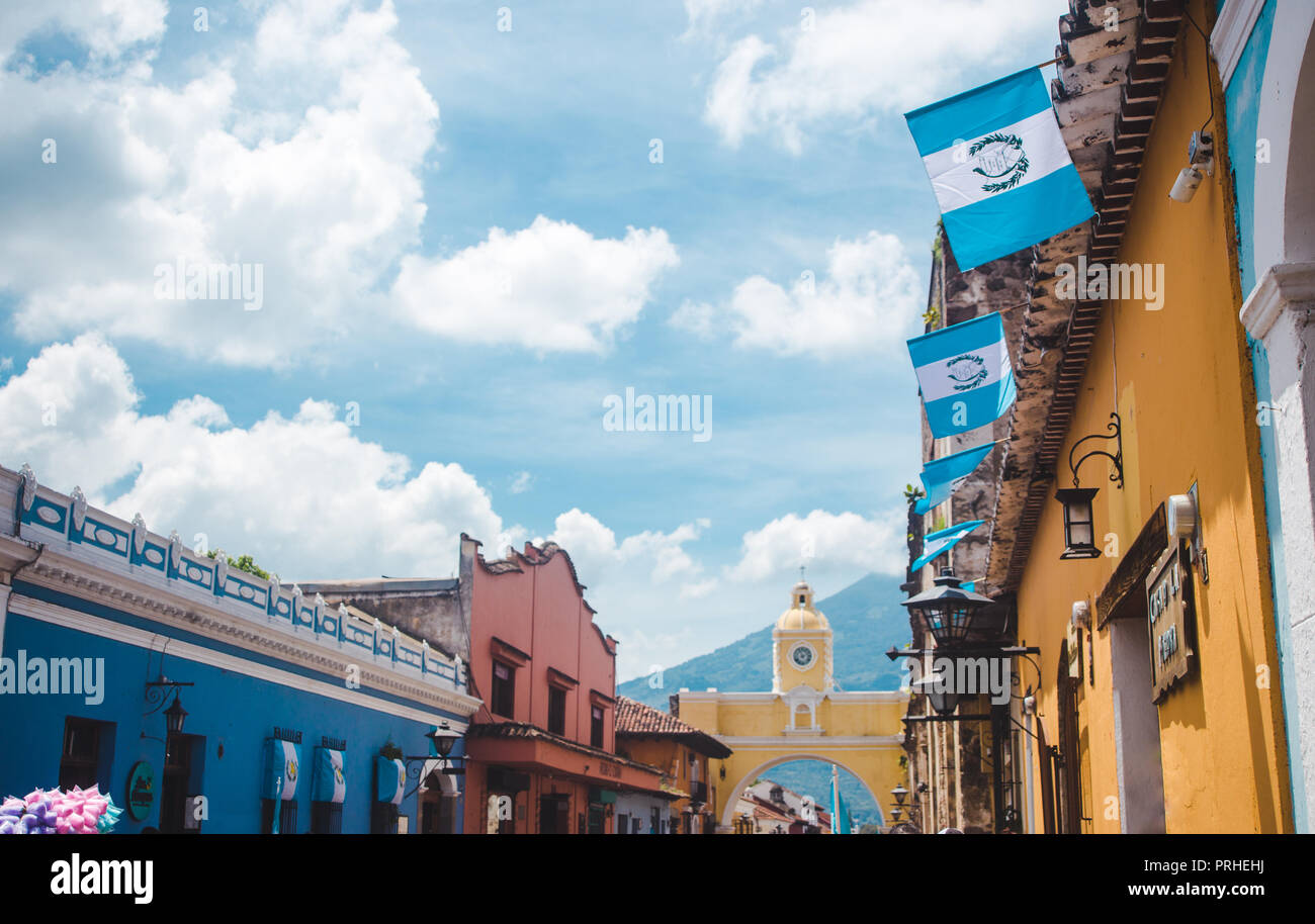 Bandiere guatemalteco fly che conduce fino al famoso arco giallo di Santa Catalina in Antigua Guatemala su un soleggiato giorno di indipendenza Foto Stock