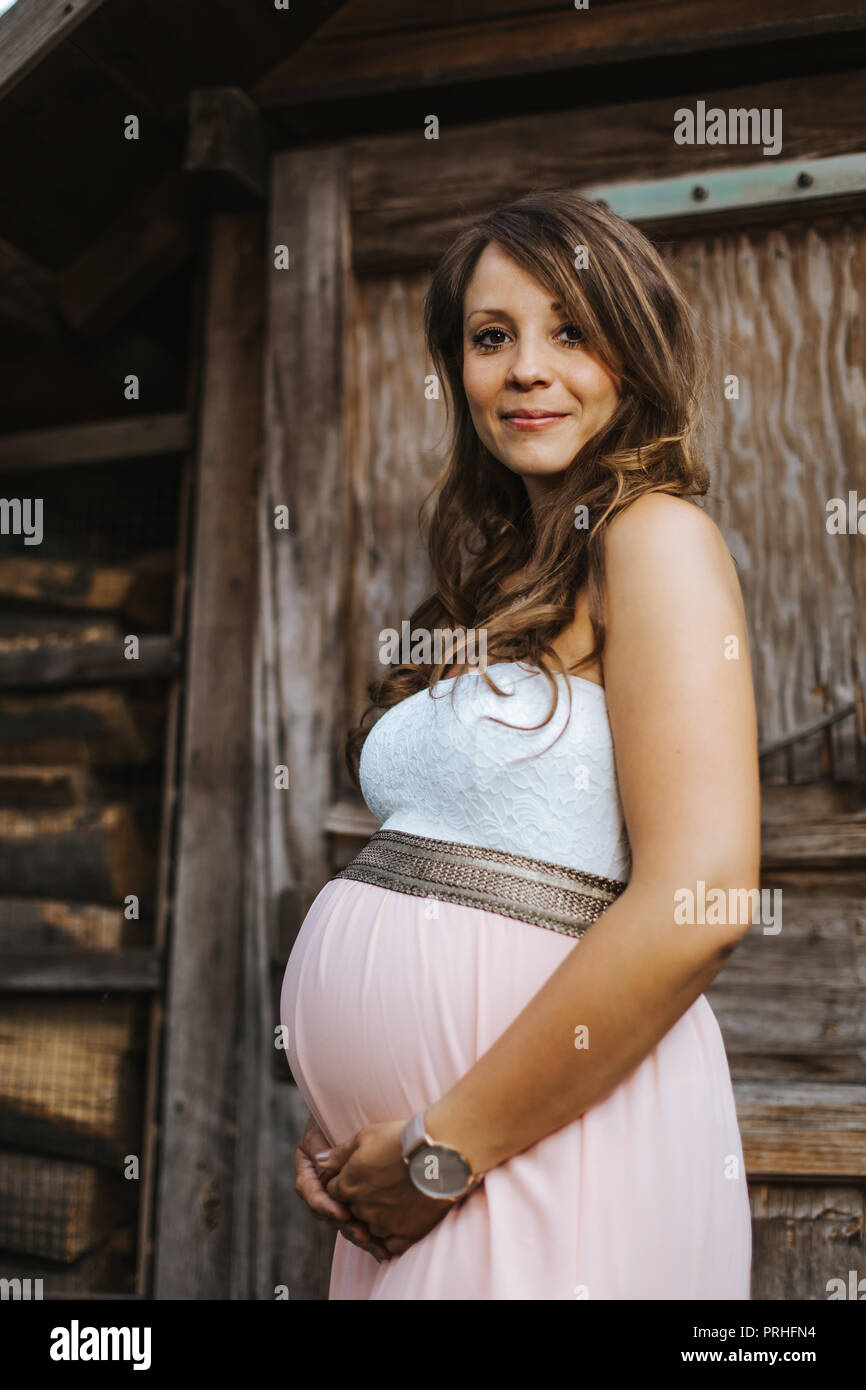 Ritratto di bella donna incinta mentre tiene il suo ventre e guardando nella telecamera Foto Stock