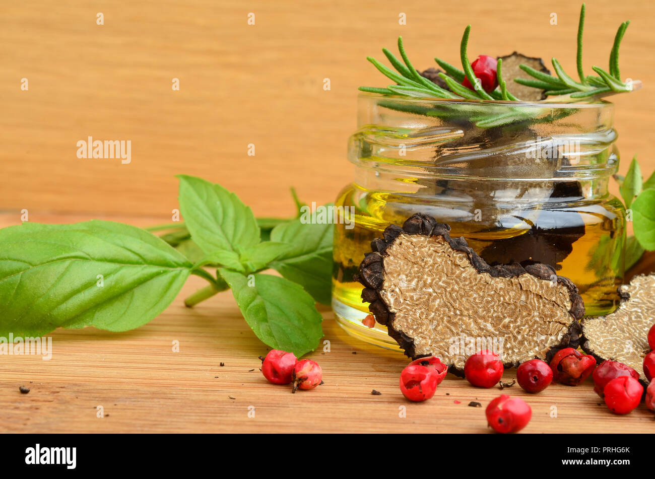 Tagliate a fette a forma di cuore di tartufo nero in olio di oliva in piccoli jarand alcune spezie fresche, basilico, origano, rosmarino e pepe rosso, vista ravvicinata Foto Stock