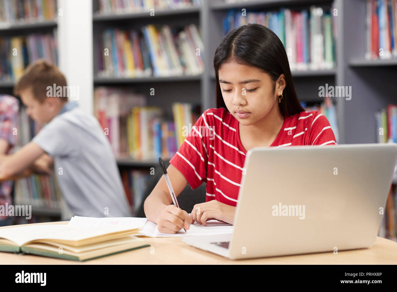 Femmina di alta scuola studente lavora al computer portatile in biblioteca Foto Stock