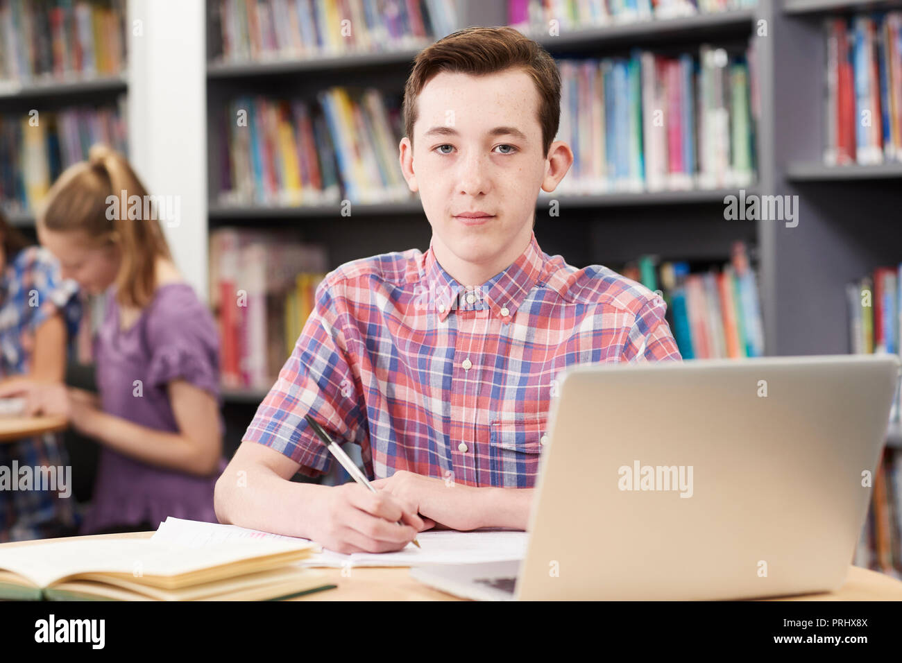 Ritratto maschile di alta scuola studente lavora al computer portatile in biblioteca Foto Stock