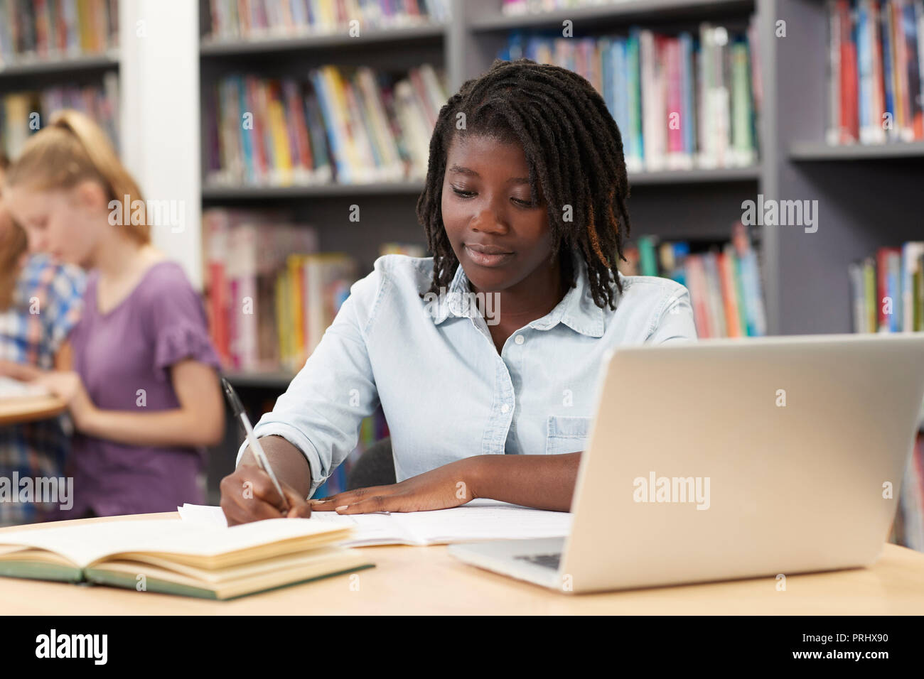 Femmina di alta scuola studente lavora al computer portatile in biblioteca Foto Stock