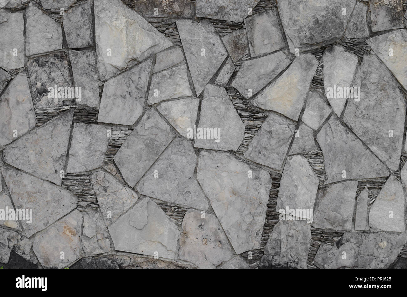Parete con pezzi rotti di pietre in forme geometriche, naturale sfondo decorativo. Foto Stock