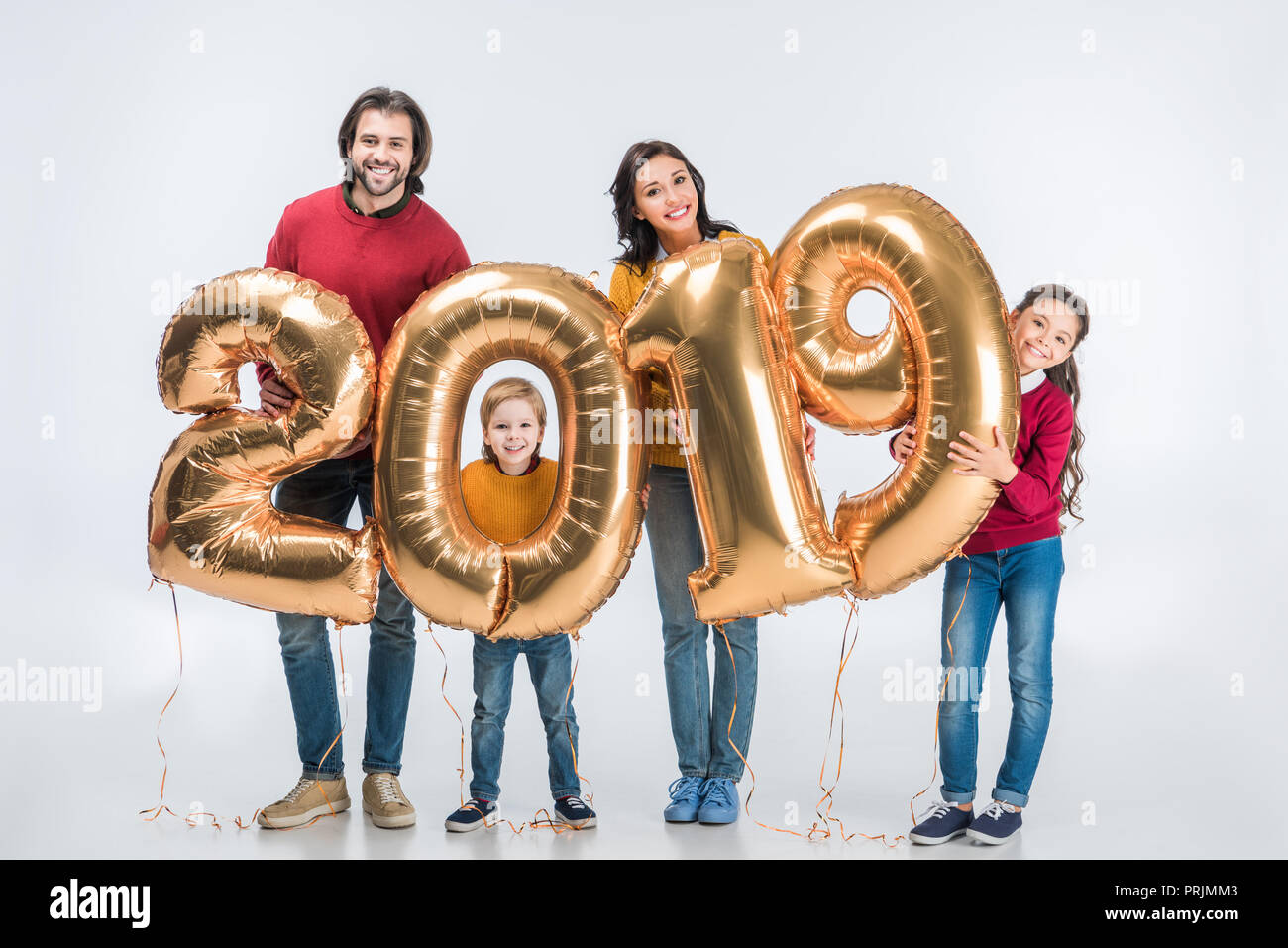 La famiglia felice azienda golden 2019 segno palloncini per il nuovo anno e guardando la telecamera isolato su bianco Foto Stock