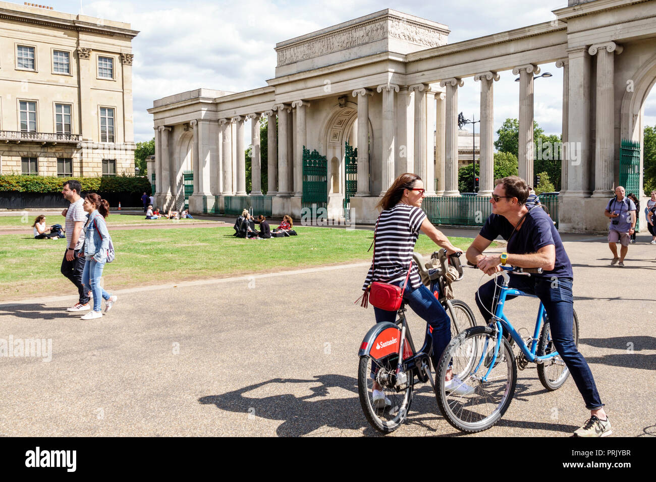Londra Inghilterra,UK,Hyde Park Corner,Decimus Burton's Ionic screen,gate,colonne,uomo uomo uomo maschio,donna donna donna donna donne,coppia,ciclista,bicicletta bicicletta bicicletta bicicletta bicicletta Foto Stock
