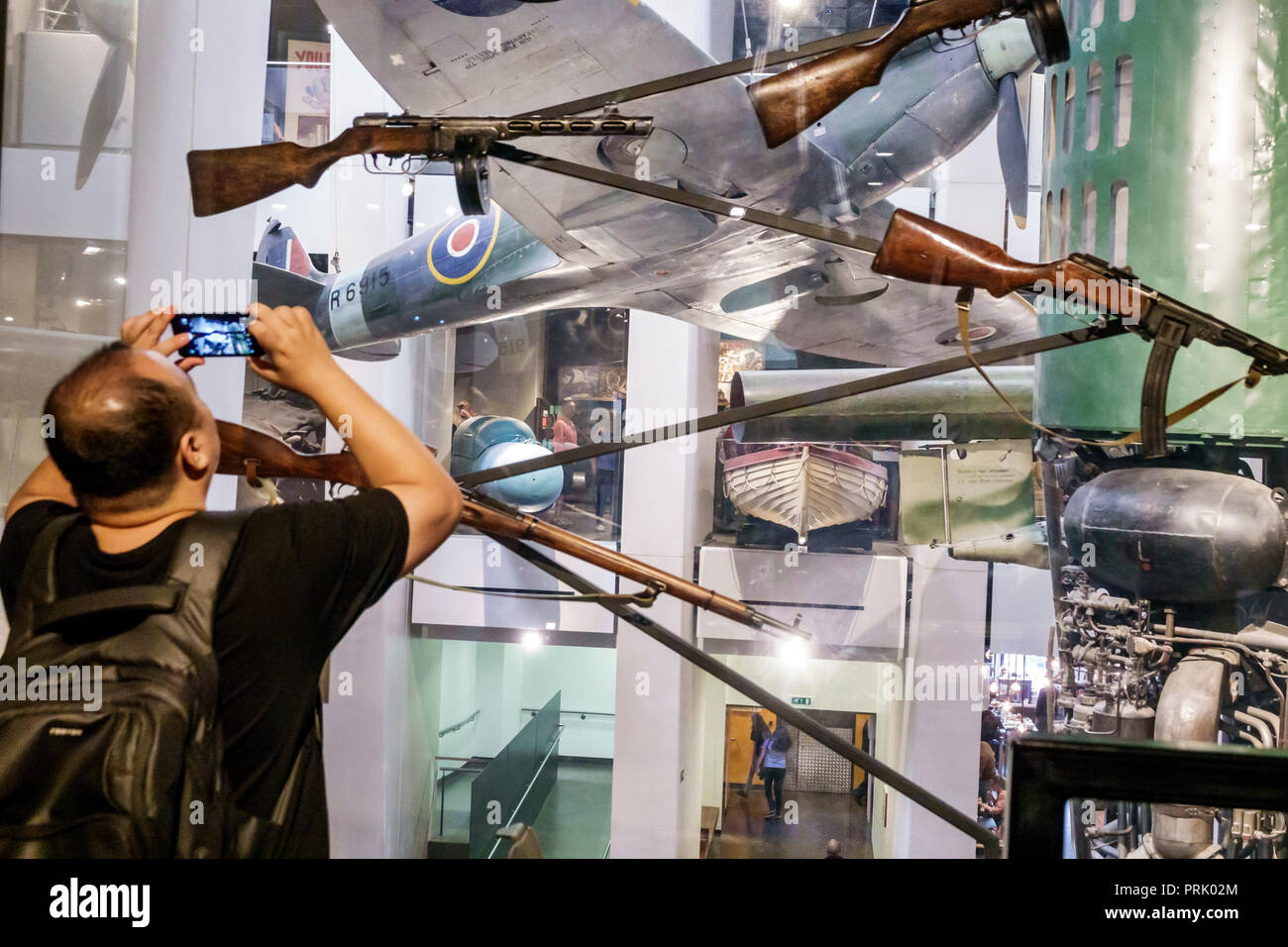 Londra Inghilterra,Regno Unito,Southwark,Imperial War Museum,archivi di armi da guerra militari,interni,mostra,armi,fucili,uomo asiatico maschio,scattare foto,s Foto Stock