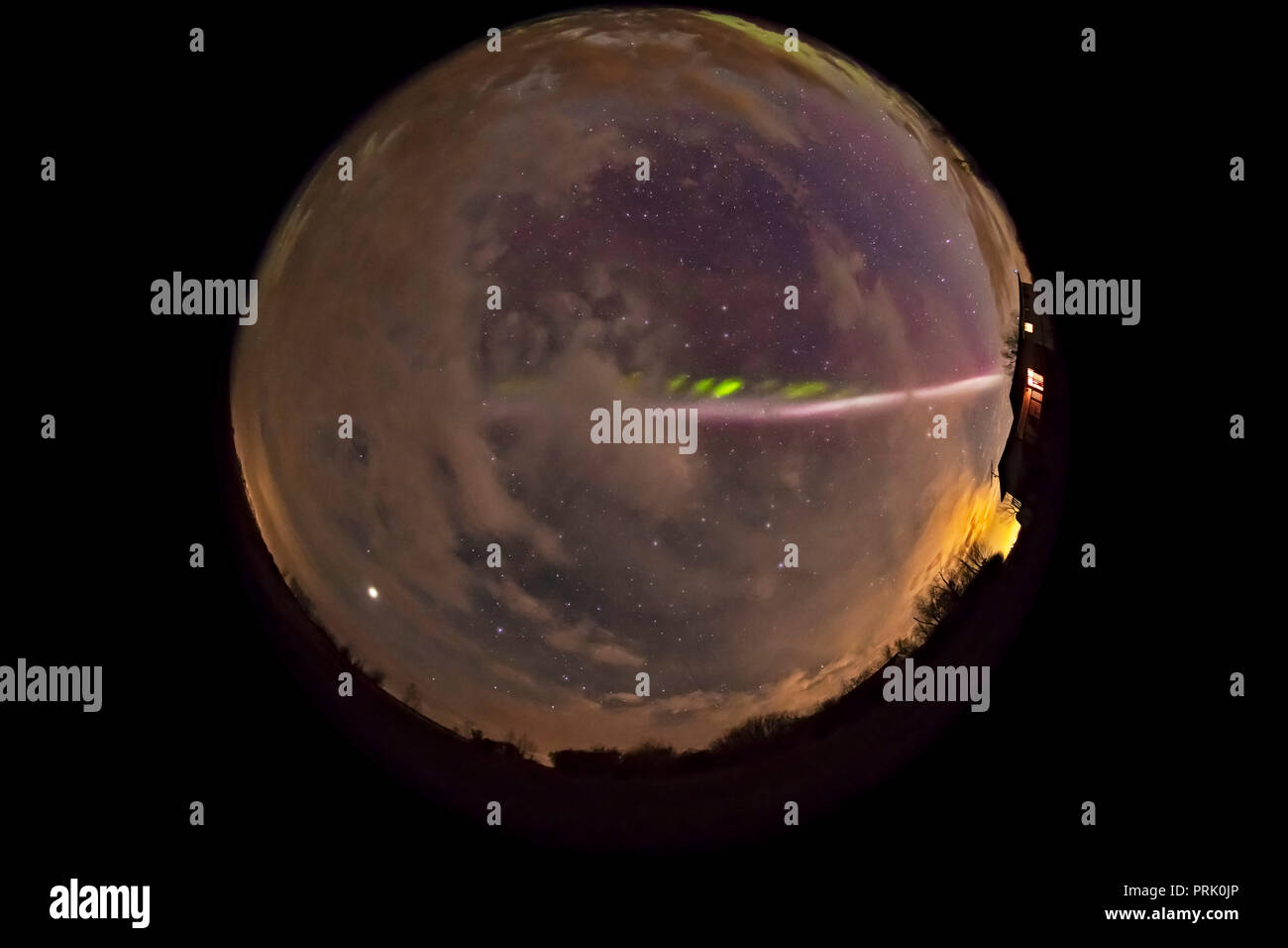 Una lente fish-eye / tutto-vista cielo dello Steve aurora arco attraverso il Cielo e nubi in maggio su 6, 2018 da casa nel sud Alberta, con una tranquilla aurora Foto Stock