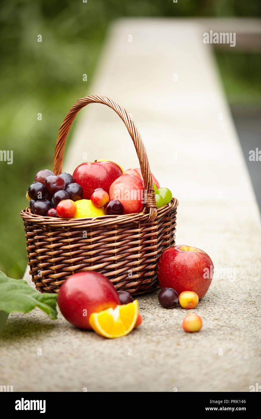 Frutti assortiti in un cesto per il picnic su una pietra esterna banco. Foto Stock