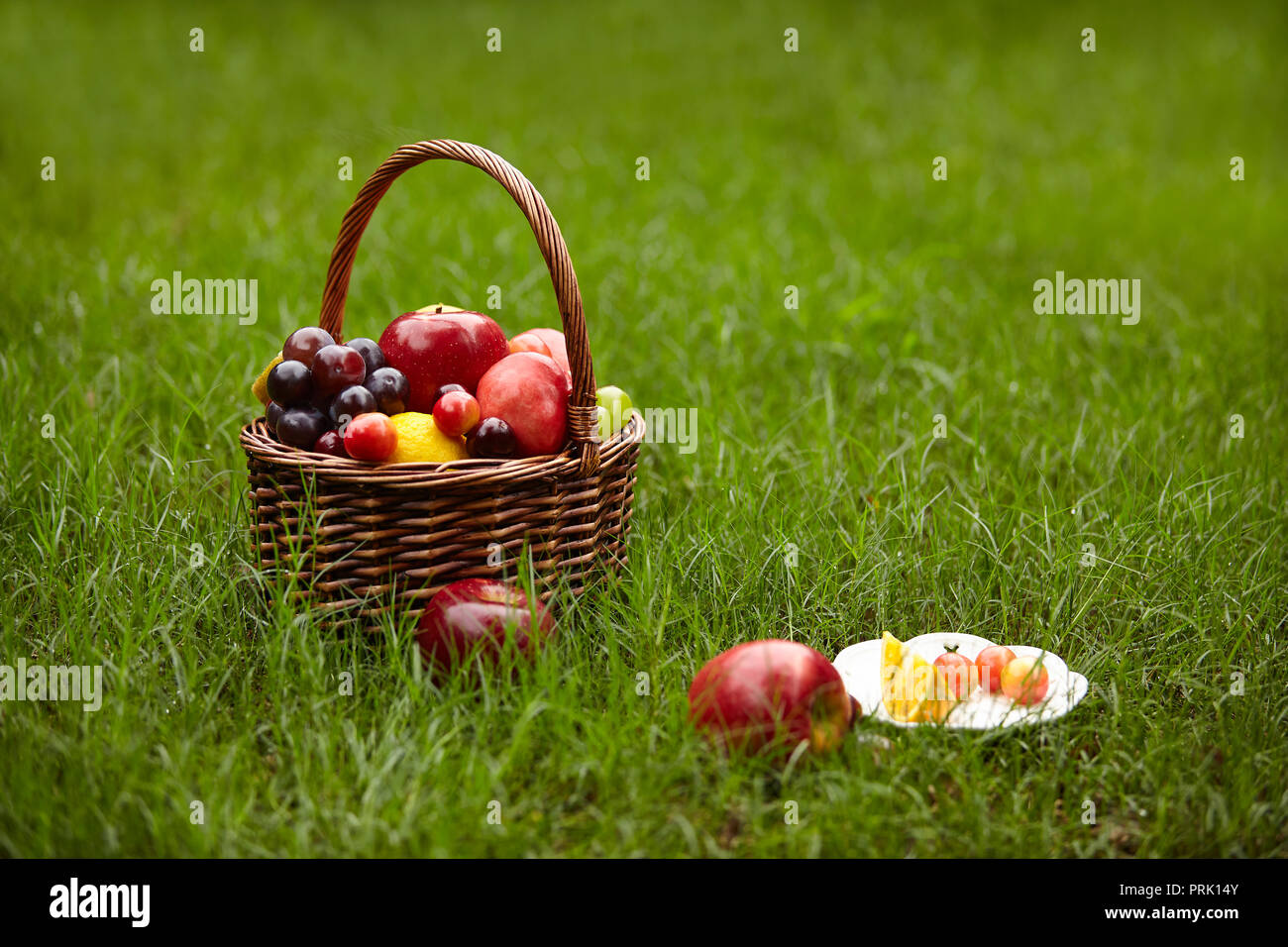 Frutti assortiti in un cesto per picnic sull'erba. Foto Stock