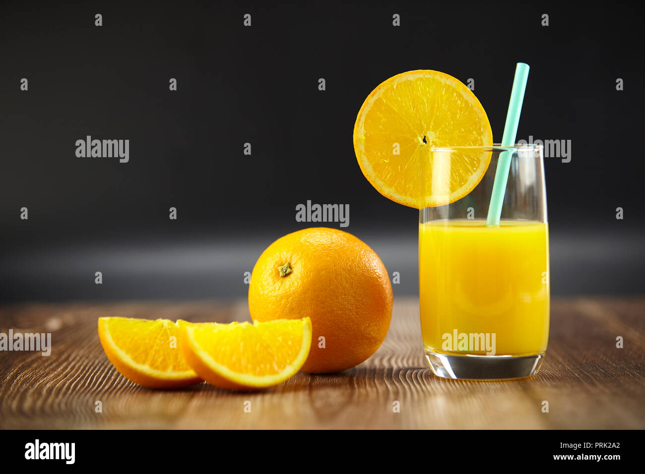 Arance e succo di arancia sul disco superficie di legno con sfondo nero. Foto Stock
