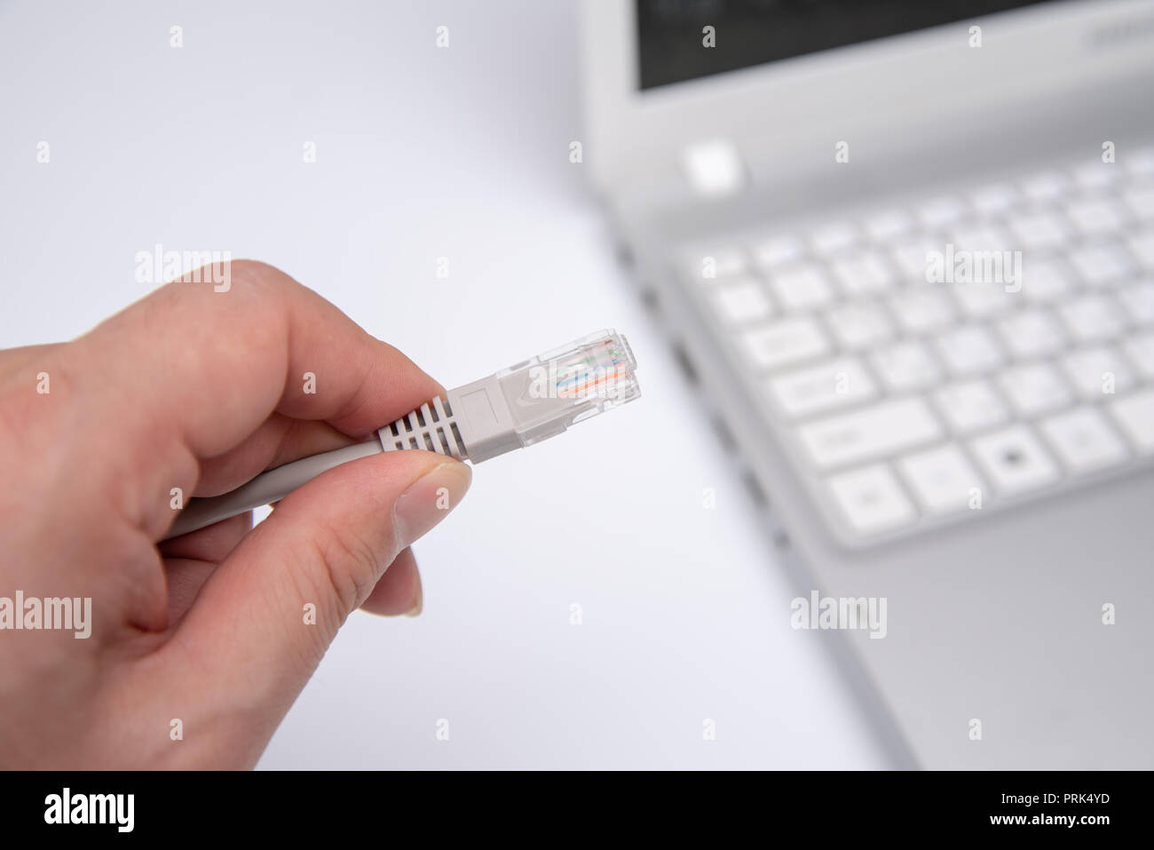 Primo piano lato cavo di collegamento per la connessione di rete a una porta LAN di un computer portatile sul tavolo bianco, concetto di collegamento del computer. Foto Stock