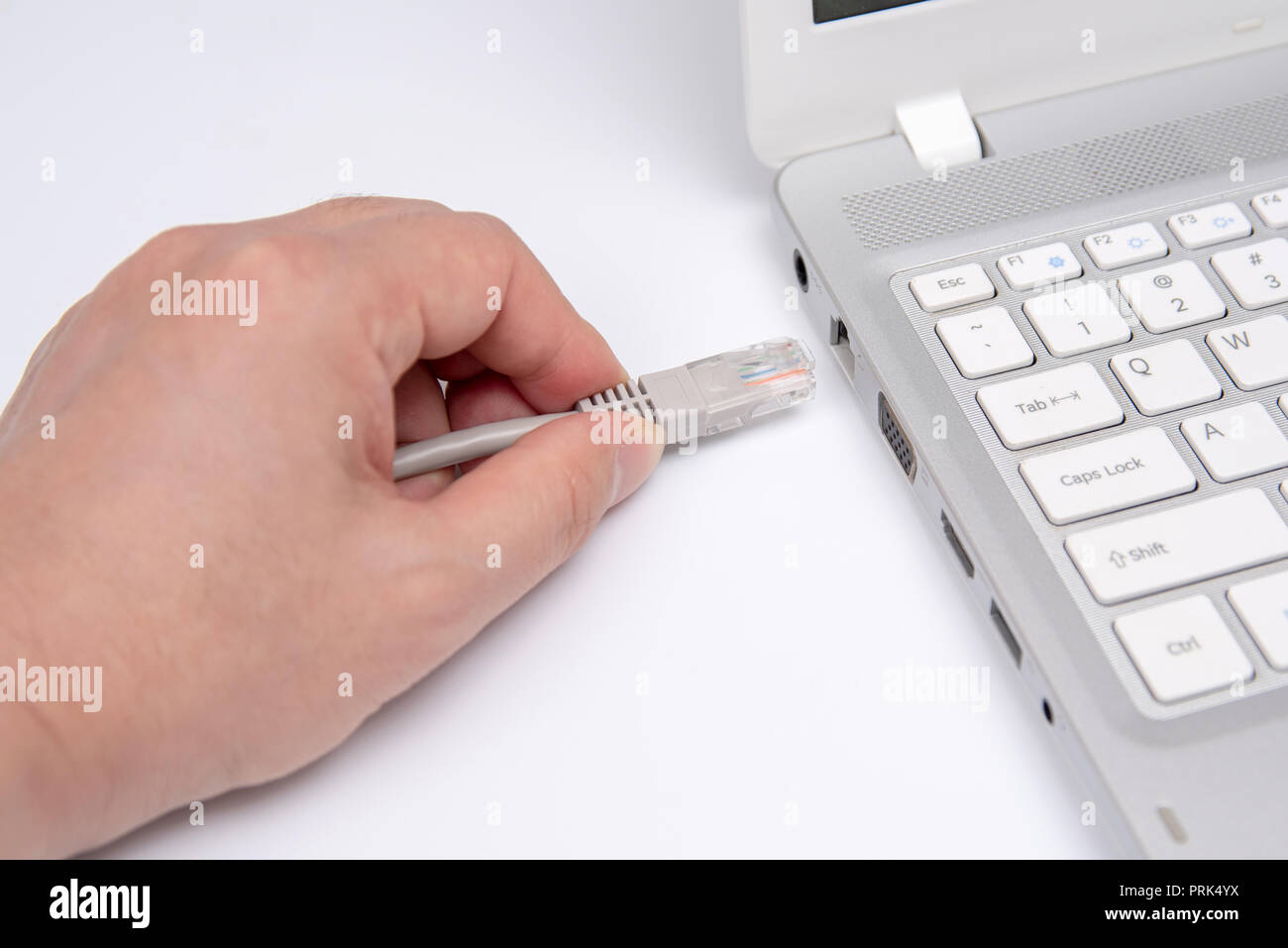Primo piano lato cavo di collegamento per la connessione di rete a una porta LAN di un computer portatile sul tavolo bianco, concetto di collegamento del computer. Foto Stock