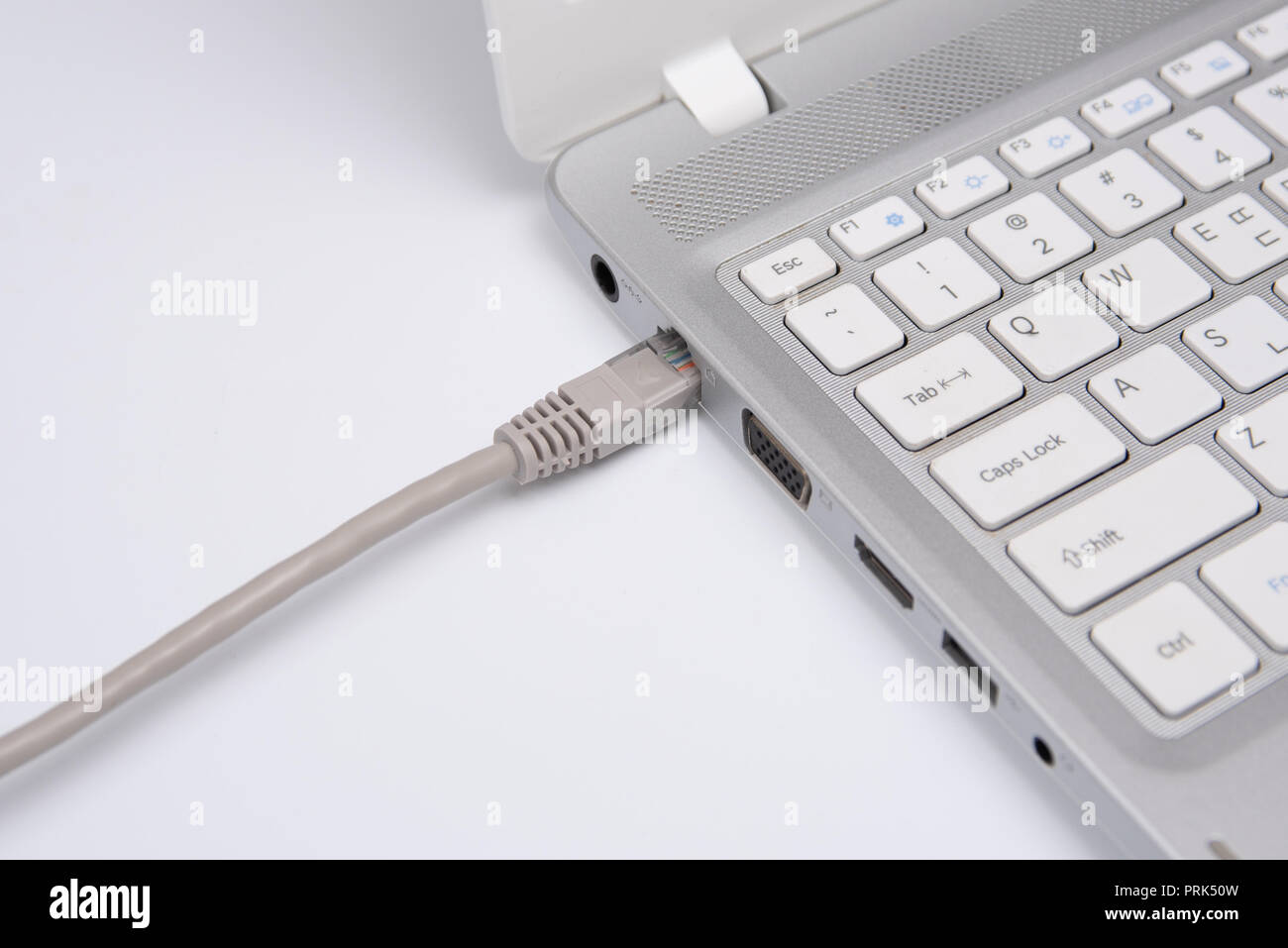 Closeup cavo di collegamento per la connessione di rete a una porta LAN di un computer portatile sul tavolo bianco, concetto di collegamento del computer. Foto Stock
