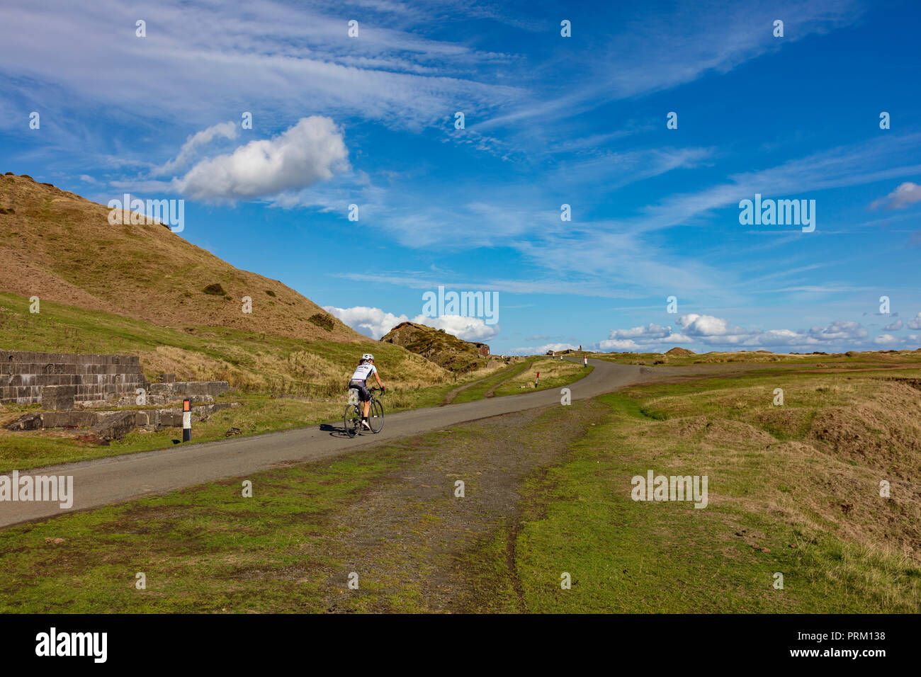 Una donna ciclista si sale la strada Titterstone Clee Hill verso la vetta, vicino a Ludlow, Shropshire, Regno Unito. Shropshire Hills AONB Foto Stock