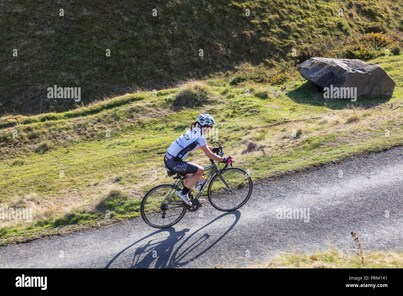 Una donna ciclista si sale la strada Titterstone Clee Hill verso la vetta, vicino a Ludlow, Shropshire, Regno Unito. Shropshire Hills AONB Foto Stock